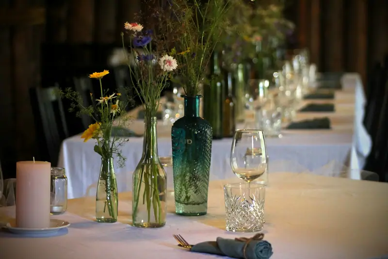 Bouteilles de verre garnies de fleurs sur une longue table