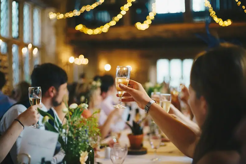 Invités levant leur verre sous des guirlandes lumineuses